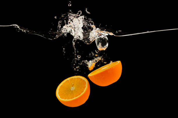 istock Falling citrus fruits. Orange halves splattering into water on black background 1210559503
