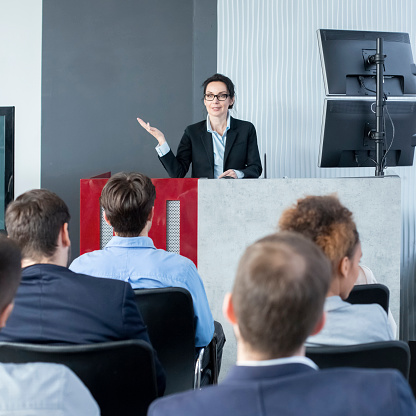 Confident CEO giving presentation to young staff in conference room, crop