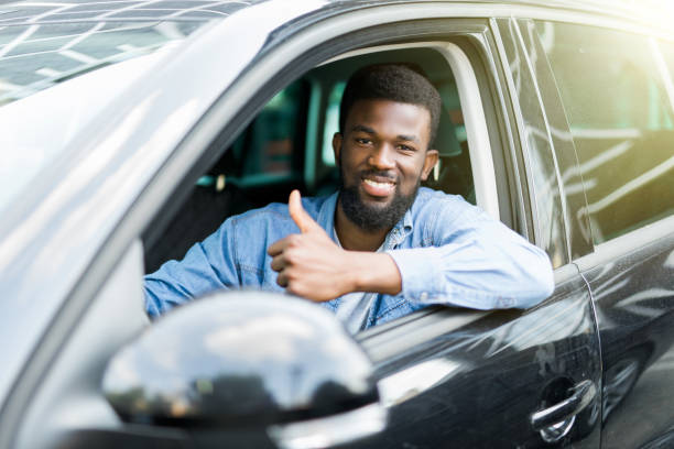 istock Young handsome african man show thumbs up while drive his car 1210561318