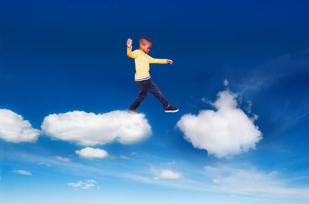 istock Little boy walking from one cloud to another 1210561327