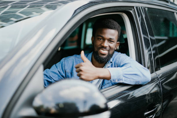 istock Young handsome african man show thumbs up while drive his car 1210561359