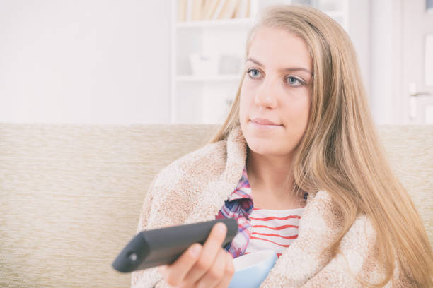 istock Woman holding tv remote control and changing TV channels 1210561735