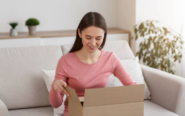 istock Young smiling girl unboxing cardboard parcel at home 1210562543