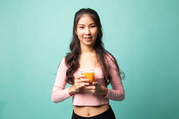 istock Young Asian woman drink orange juice. 1210563105