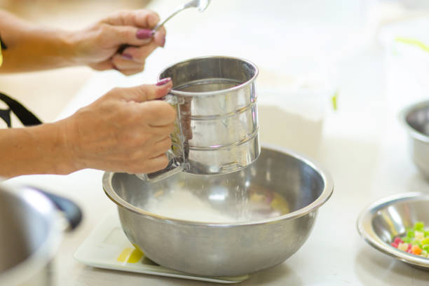 cooking baking. cook sifts the flour a - cake making mixing eggs imagens e fotografias de stock