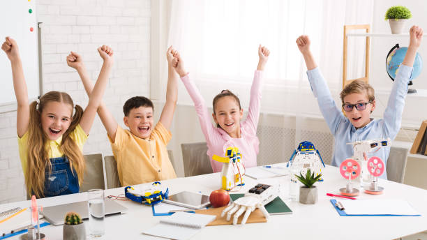 istock Overjoyed children cheering and raising hands at robotics class 1210564144