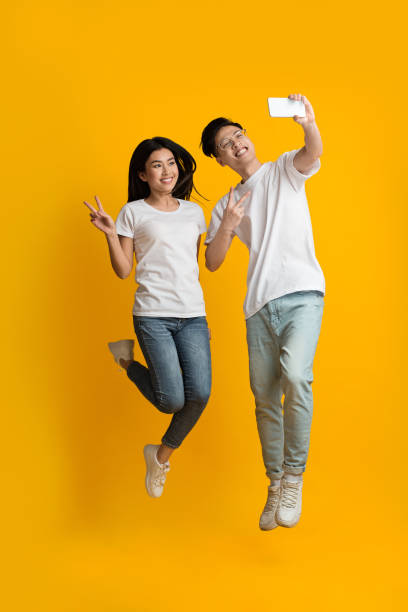 istock Beautiful asian couple taking selfie while jumping up 1210564503