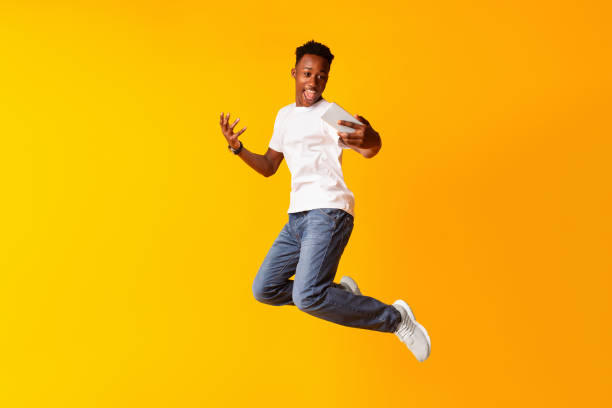 istock African guy jumping for connecting the internet on his cell phone 1210564560