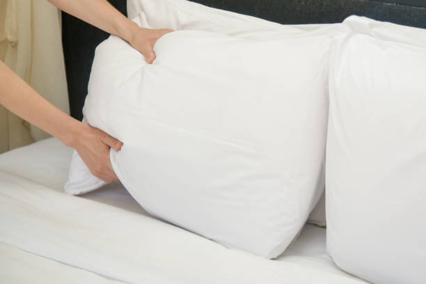 istock Hotel room service. Hands set up white pillow on the bed. 1210564771