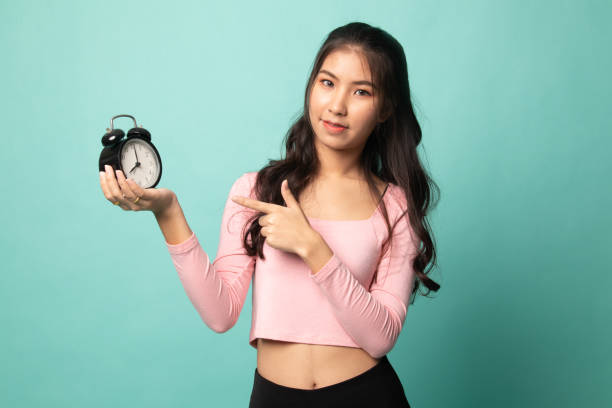 istock Young Asian woman point to a clock. 1210565512