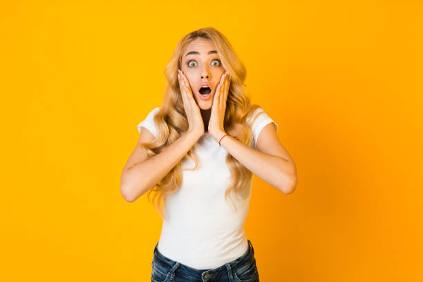 istock Shocked girl with open mouth touching her cheeks with hands 1210565727