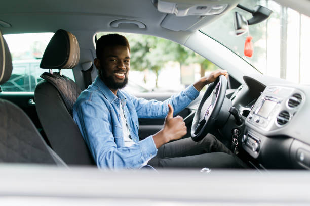 istock Handsome african man show thumbs up inside car 1210565745