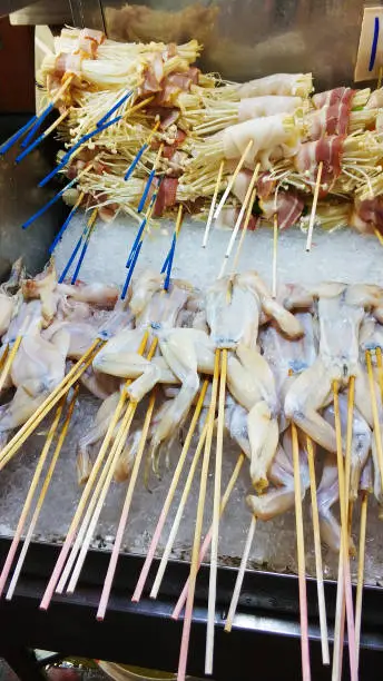 Photo of Asian street food on sticks. Raw chicken wings for barbecue