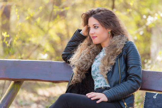istock Beautiful woman resting a bench in the park 1210571089