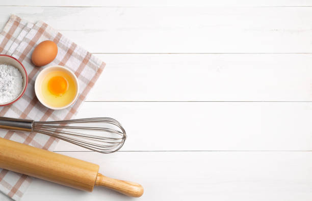 istock Rolling pin, tapioca flour, egg, oven glove and a whisk on vintage wooden table. 1210572697