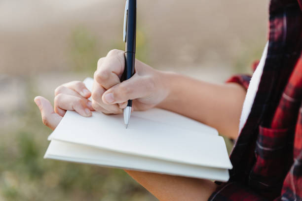istock Hand of young girl writing on note book with pen. 1210572921