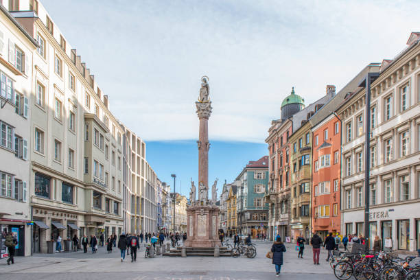 people walking in the maria theresien straße (street) next to the st. ann's column at innsbruck old town in austria. - inn history built structure architecture imagens e fotografias de stock