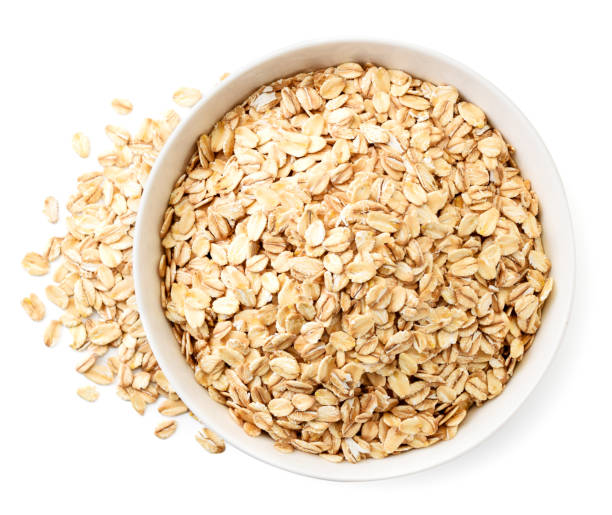 istock Oatmeal in a plate and scattered on a white background. The view from top 1210573890