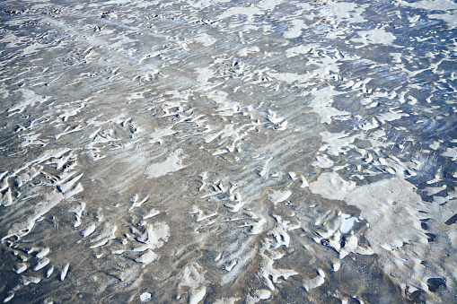 A part of sandy beach covered with ice in winter