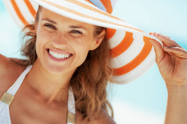 istock smiling young woman in swimsuit and beach hat 1210577135