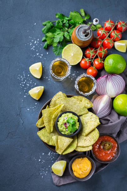 istock Corn tortilla chips nachos with guacamole, chili, cheese salsa, tequila 1210577293