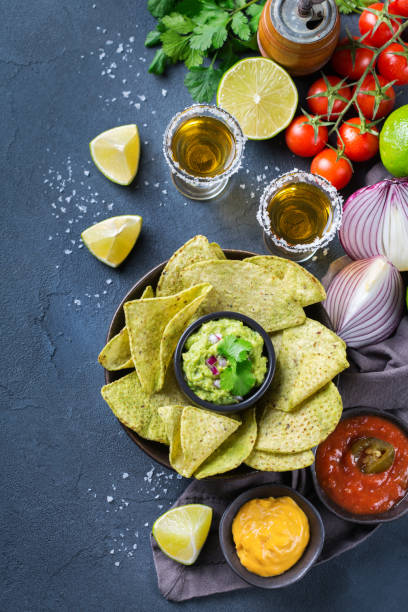istock Corn tortilla chips nachos with guacamole, chili, cheese salsa, tequila 1210577299