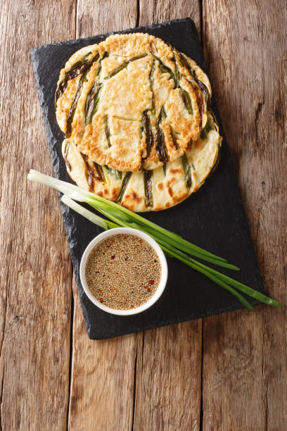 istock Basic recipe Pajeon Korean pancakes with green onions close-up on a slate board. Vertical top view 1210578406