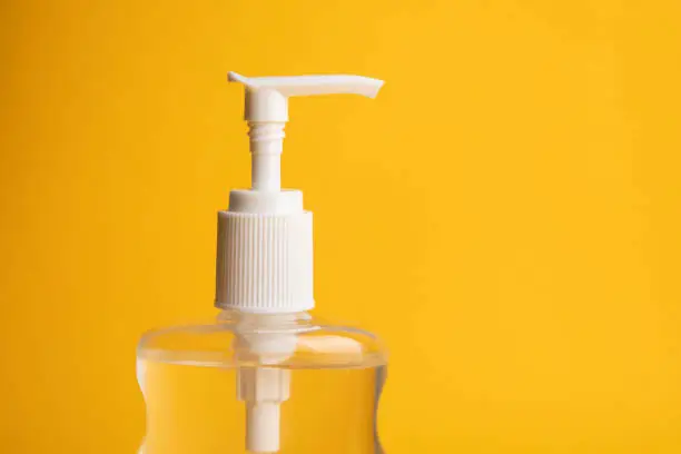 A close up of a bottle of hand sanitizer photographed on a yellow background with copy space.
