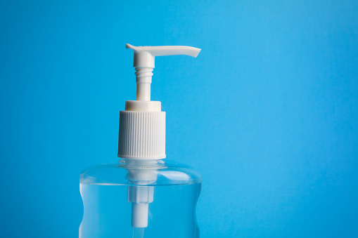 A close up of a bottle of hand sanitizer on a blue background.