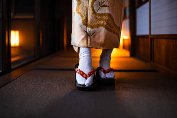 Traditional Japanese ryokan house with tatami mat floor, shoji sliding paper doors and closeup of woman in kimono and geta shoes tabi socks walking in corridor Traditional Japanese ryokan house with tatami mat floor, shoji sliding paper doors and closeup of woman in kimono and geta shoes tabi socks walking in corridor yukata photos stock pictures, royalty-free photos & images