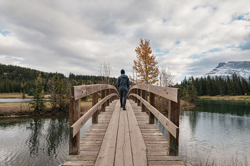 Man traveler walking cross over wooden bridge in autumn at Cascade Ponds, Banff national park, Canada