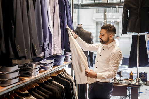 Young Man shopping for clothes in a menswear shop.