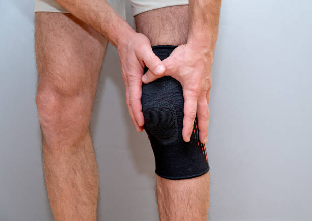 istock male hands hold knee with black elastic bandage 1210588153