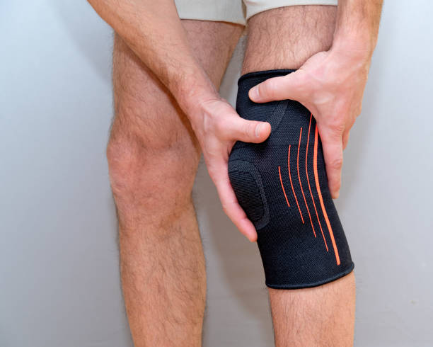istock male hands hold knee with black elastic bandage 1210588512