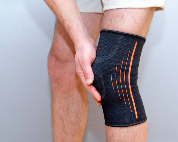 istock male hands hold knee with black elastic bandage 1210589110
