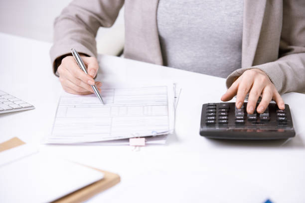 istock Hands of young elegant accountant with pen over financial document 1210589453