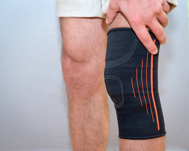 istock male hands hold knee with black elastic bandage 1210590612