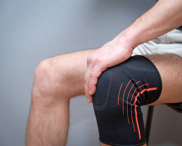 istock male hands hold knee with black elastic bandage 1210590701