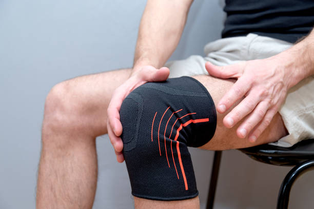 istock male hands hold knee with black elastic bandage 1210590845