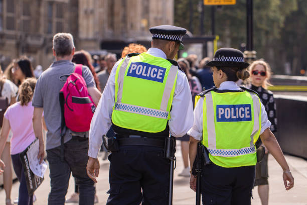 Male and female Asian metropolitan police officers patrol the crowds of tourists outside the Hoses of Parliament in Westminster, London, UK stock photo