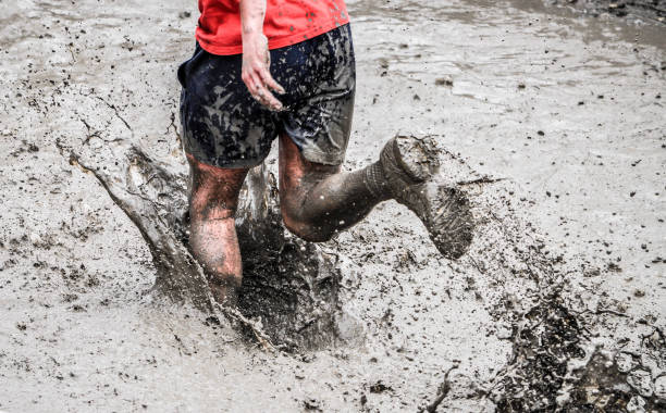 um participante de uma corrida fisicamente exigente está correndo pela lama - mud run - fotografias e filmes do acervo