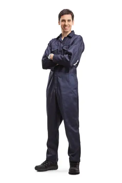Full length portrait of a young male worker in an overall uniform posing and smiling isolated on white background