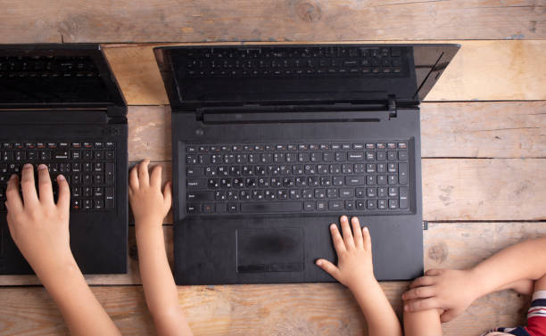 istock Boys using a laptop on wooden table, top view 1210595099