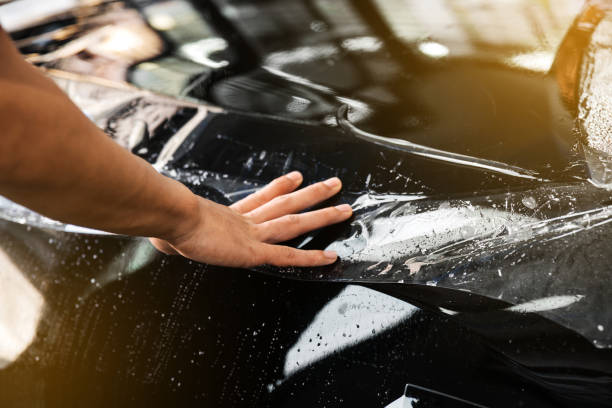 istock PPF installation process, close-up on transparent film and bubble on hand touching a car tail light and trunk. 1210595687