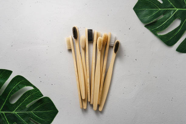 Several bamboo toothbrushes on a light concrete background. Top view with copy space. stock photo