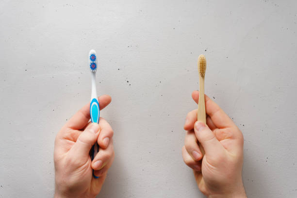 Male hands hold toothbrushes on a light gray concrete background, top view. stock photo