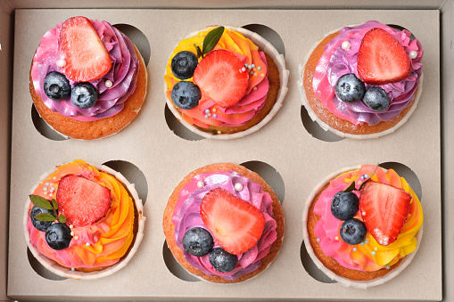 Cakes with fresh fruit and berries in a cardboard box. Top view, close -up