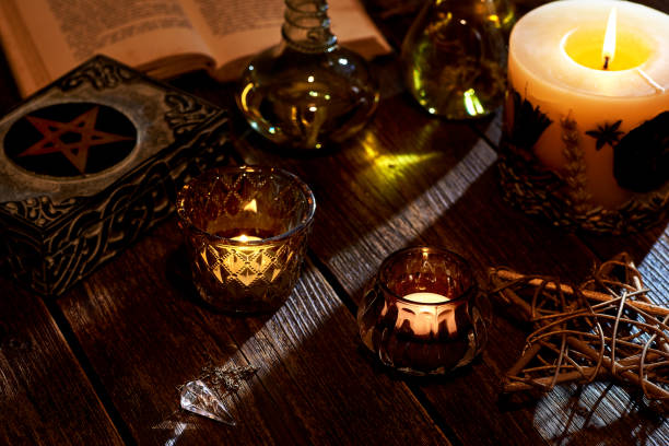 istock Still life with burning candle on old wooden table top, magic book and box with pentagram. Suitable for magic or esoteric. 1210603036