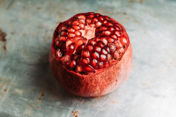 Broken red ripe pomegranate fruit on the dark rustic background