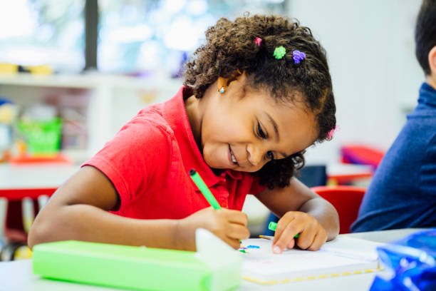 istock Hispanic elementary schoolgirl drawing in the classroom 1210604301